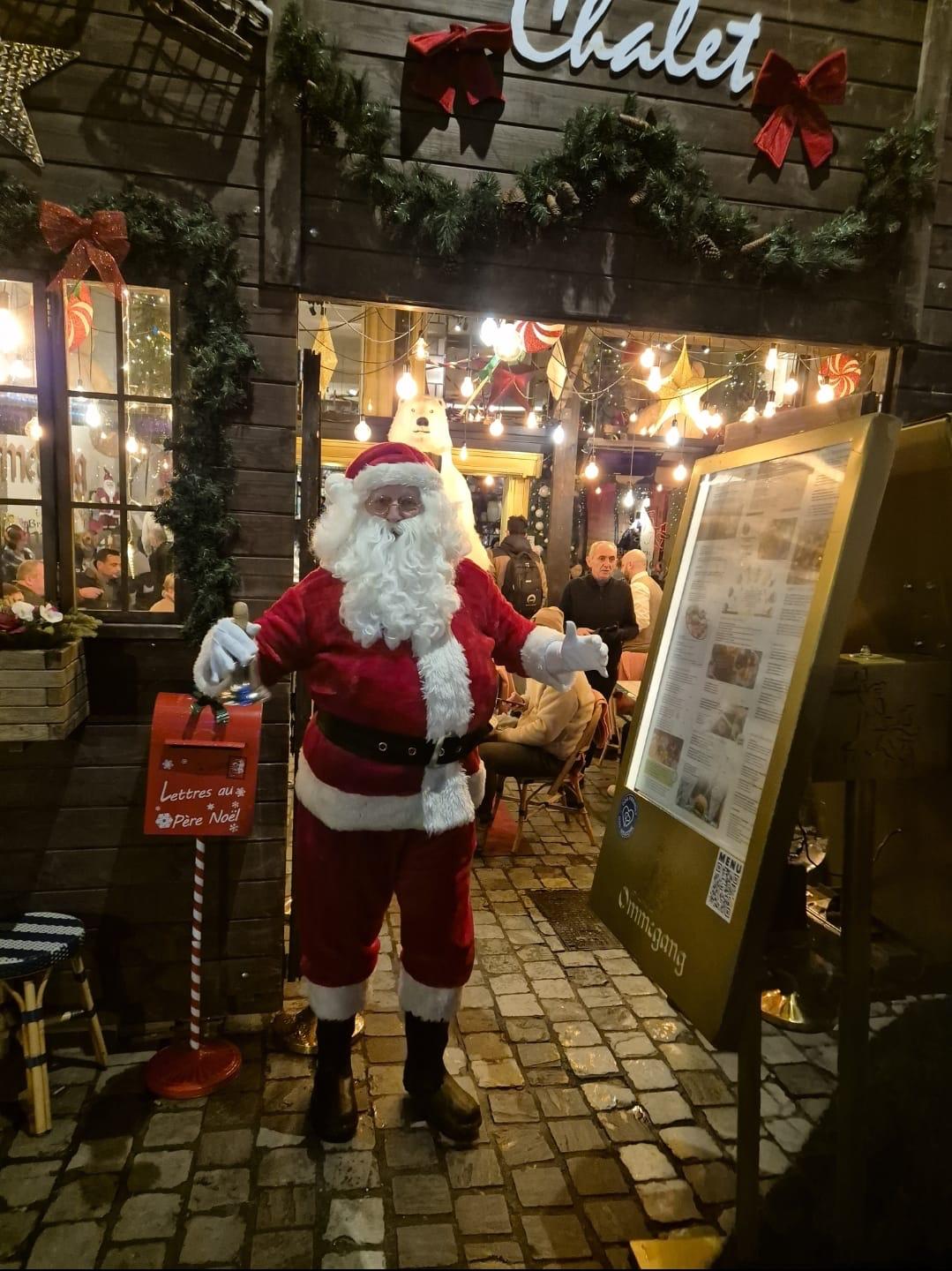 LE PÈRE NOËL devant un chalet de Noël