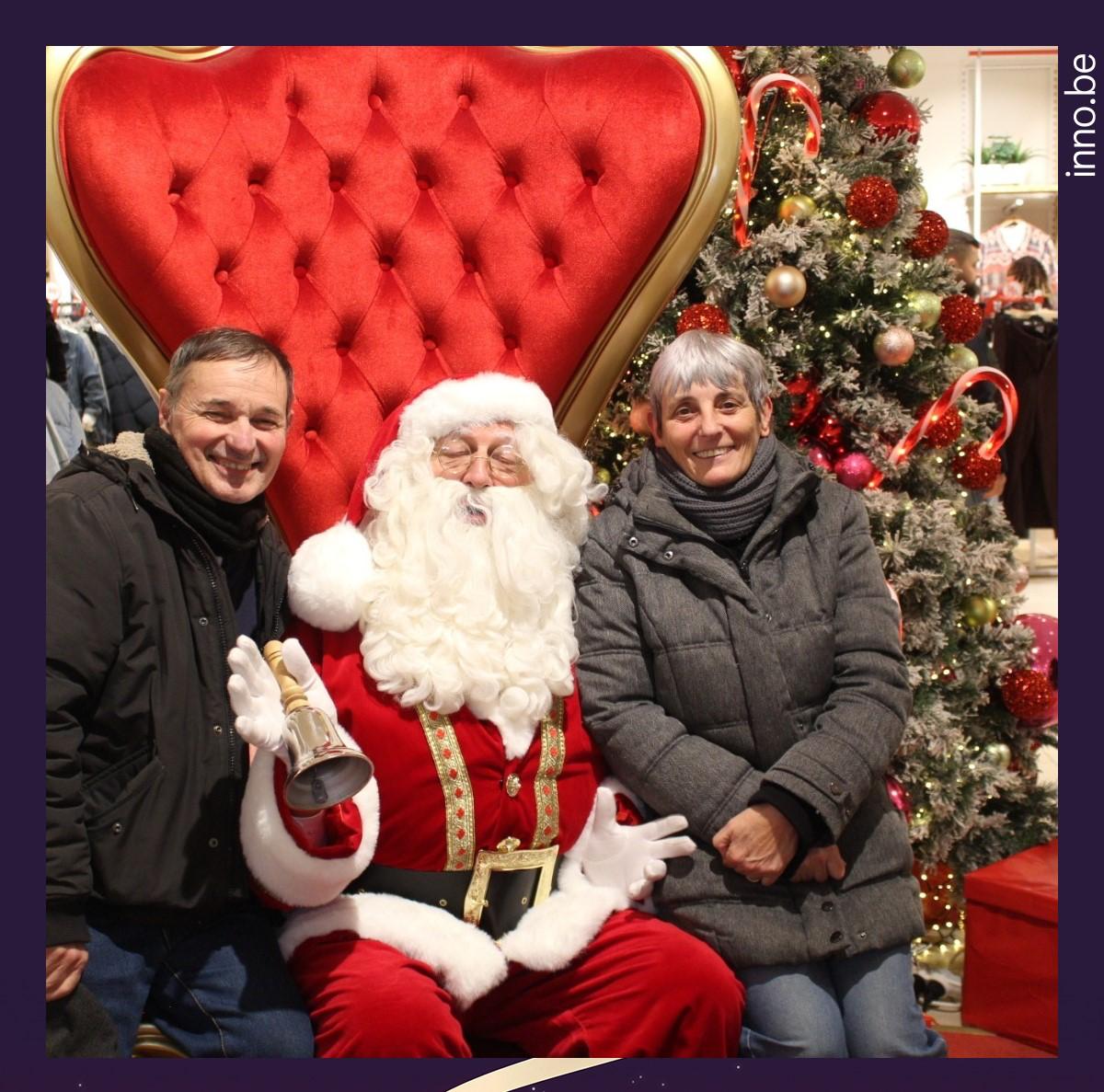 LE PÈRE NOËL posant avec des visiteurs devant le sapin